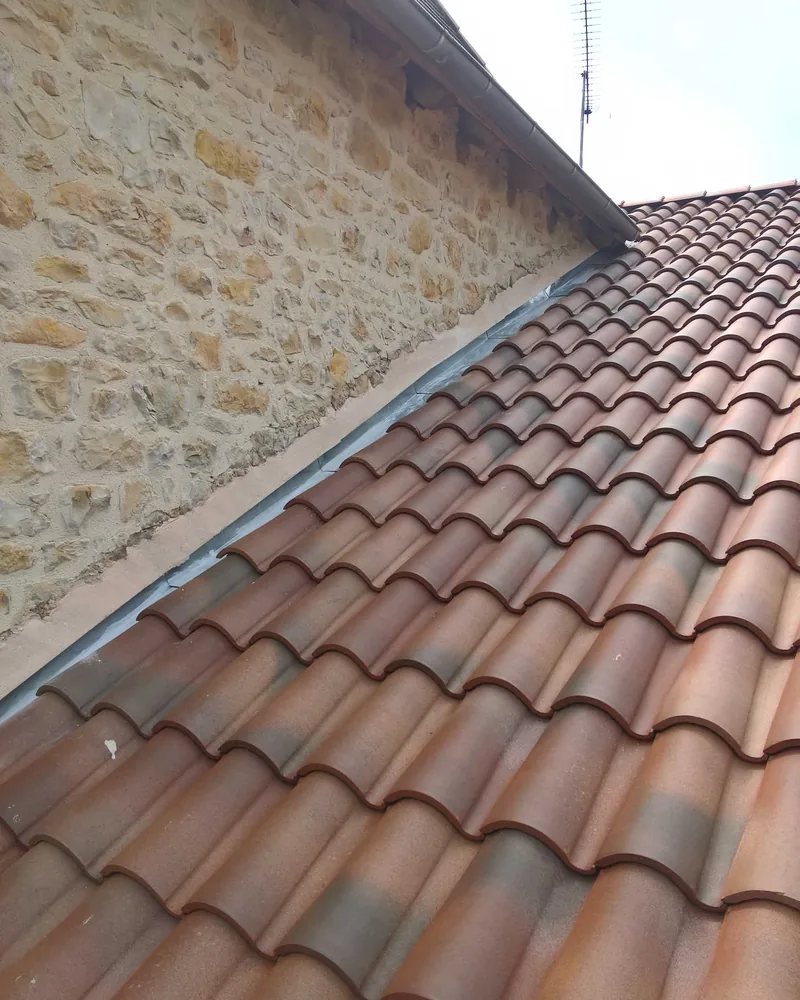 Jonction entre une toiture ancienne en pierre et une couverture neuve en tuiles, au Passage