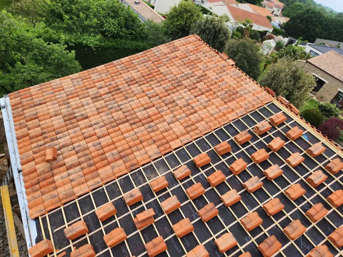 Toiture en cours de pose avec écran de sous-toiture visible et tuiles empilées